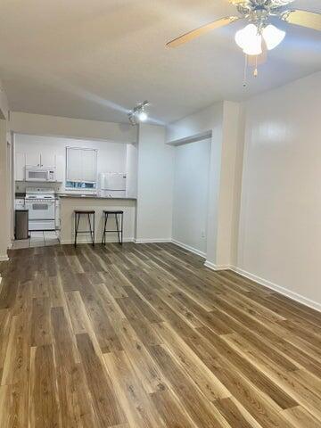 An open-concept living area features wood-look flooring and a kitchen with a breakfast bar — 4736 Chancellor Drive # 13, Jupiter FL 33458, JUPITER, FL