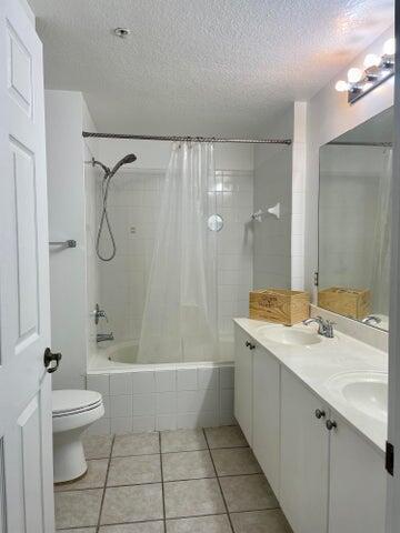 A bathroom features a white vanity, a toilet, and a shower-tub combination with white tiles — 4736 Chancellor Drive # 13, Jupiter FL 33458, JUPITER, FL