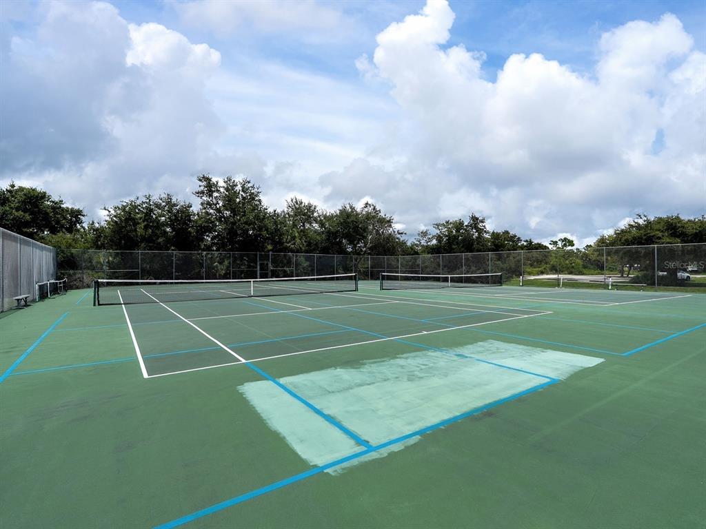 An outdoor tennis court with a green surface and a chain-link fence — 104 ARROW LANE, ROTONDA WEST, FL