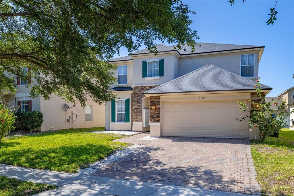A two-story house with a stone-accented facade, a two-car garage, and a brick paver driveway — 13247 HATHERTON CIRCLE, ORLANDO, FL