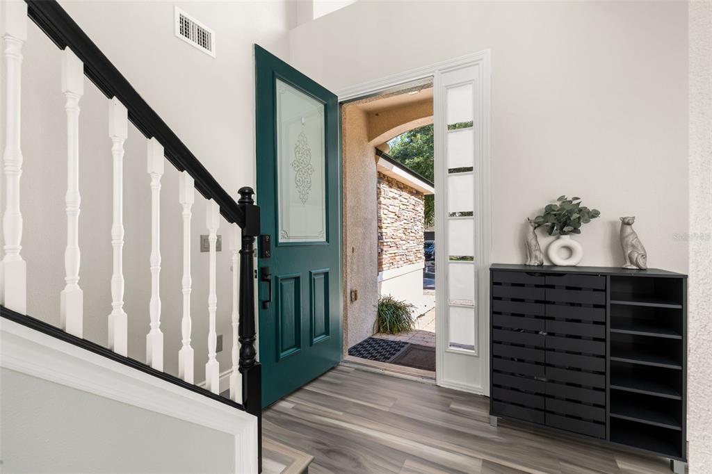 An entryway features a teal front door, wood-look flooring, a staircase, and a black cabinet — 13247 HATHERTON CIRCLE, ORLANDO, FL