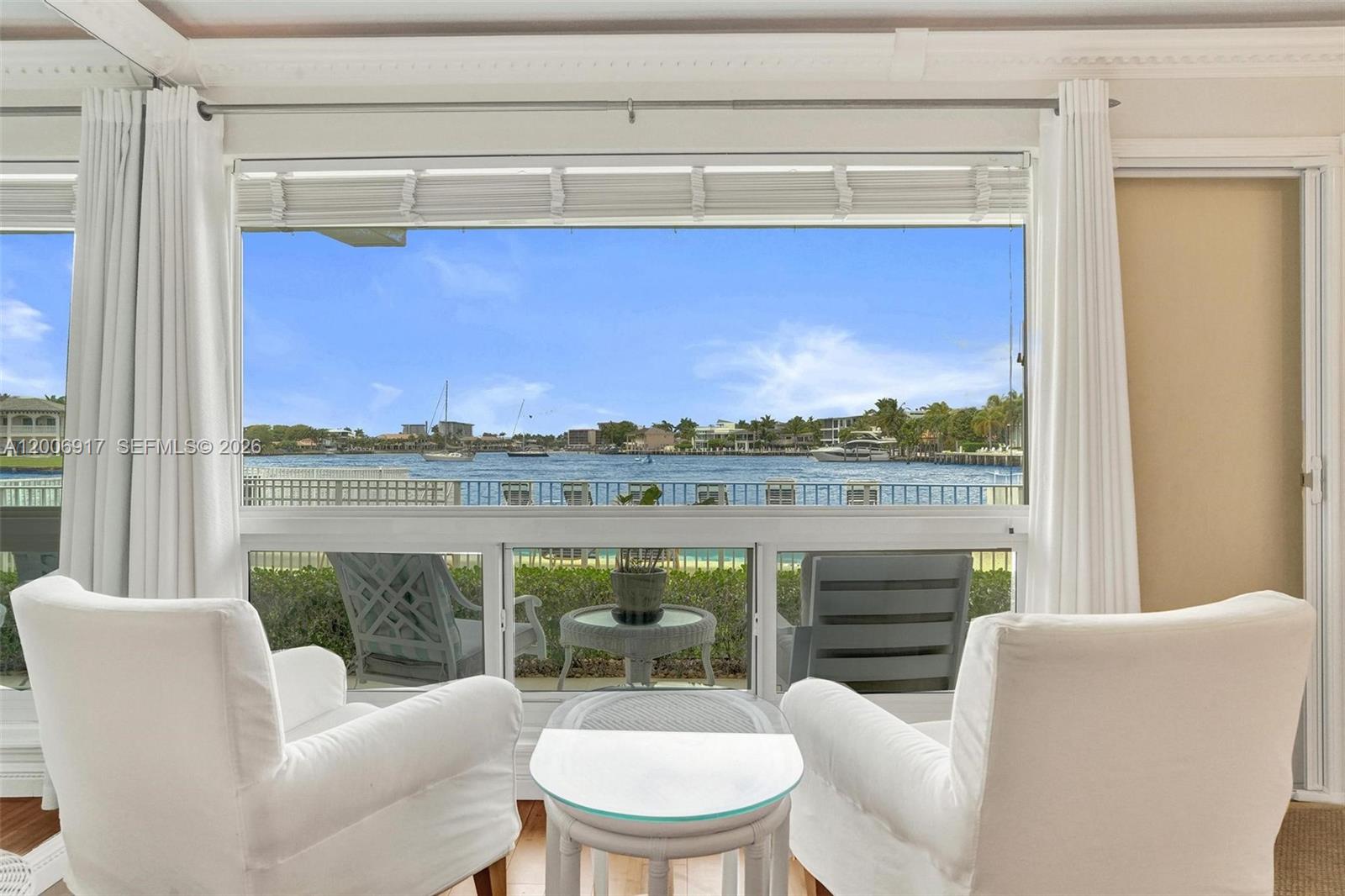 A room with two white armchairs faces a large window overlooking a waterfront view — 1105 S Riverside Dr # 107, Pompano Beach FL 33062, POMPANO BEACH, FL