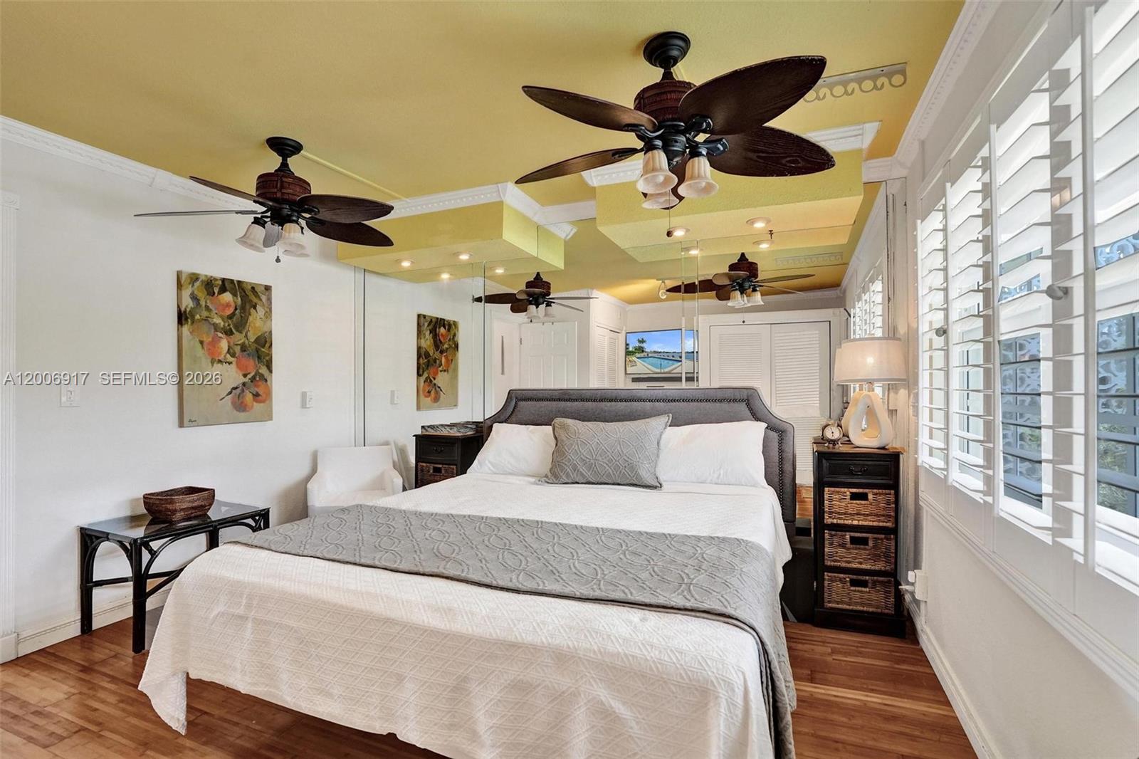 A bedroom features a yellow ceiling, mirrored walls, two ceiling fans, and a queen bed — 1105 S Riverside Dr # 107, Pompano Beach FL 33062, POMPANO BEACH, FL
