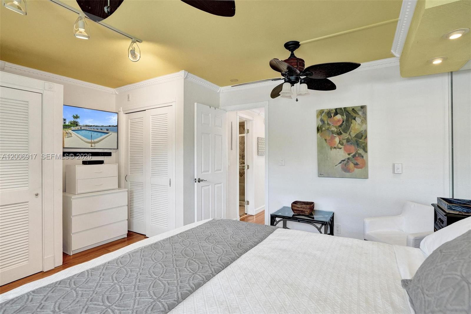 A bedroom features a bed, a dresser with a television, and a ceiling fan — 1105 S Riverside Dr # 107, Pompano Beach FL 33062, POMPANO BEACH, FL