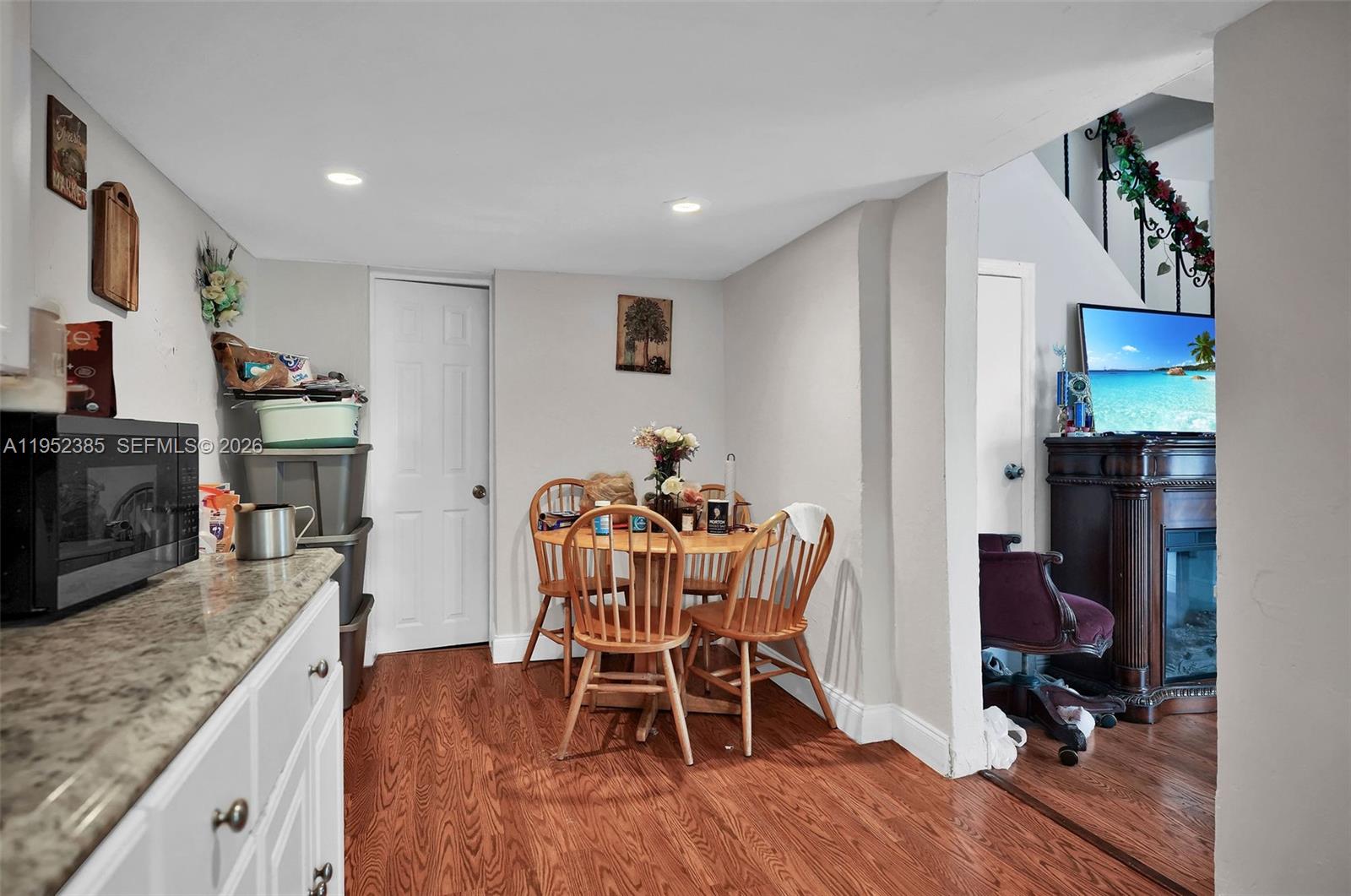 A kitchen area features a small wooden dining table, white cabinets, and wood-look flooring — 2105 NW 1st St, Miami FL 33125, MIAMI, FL