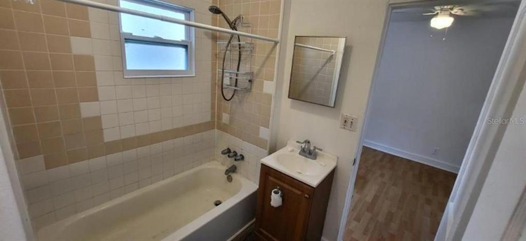 A bathroom features a bathtub with tan and white wall tiles and a small vanity — 912 ENGMAN STREET, CLEARWATER, FL