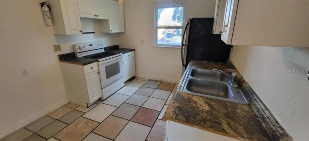 A kitchen with white cabinets, a white stove, a double sink, and tiled flooring — 912 ENGMAN STREET, CLEARWATER, FL