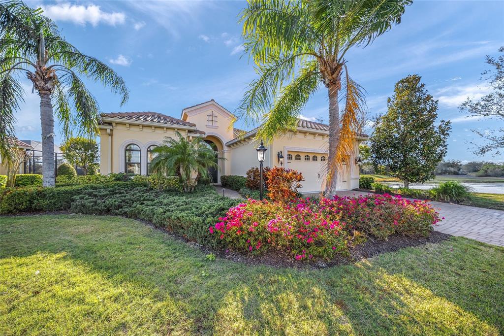 A single-story stucco house with a tile roof, palm trees, and a landscaped front yard — 7108 CALLANDER COVE, LAKEWOOD RANCH, FL