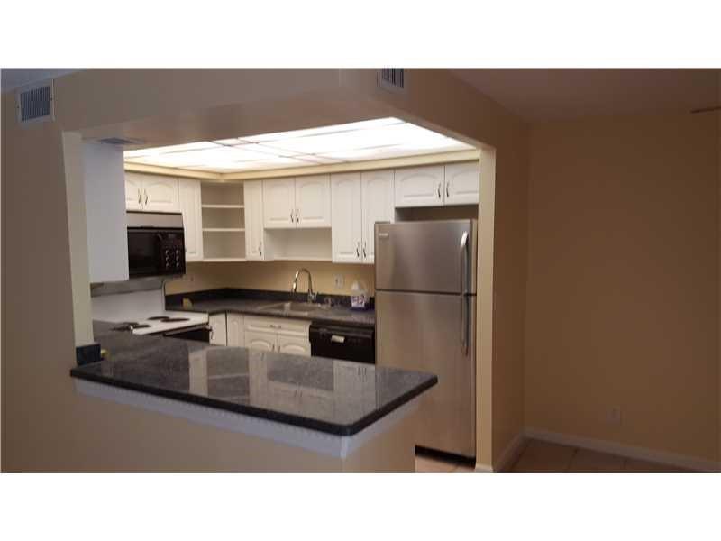 A kitchen with white cabinets, dark countertops, and stainless steel appliances viewed from a counter — 1307 Partridge # 67, Pompano Beach FL 33064, POMPANO BEACH, FL