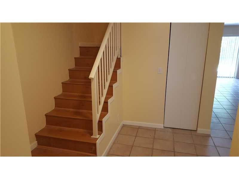 A staircase with wooden steps and a white railing sits beside a white closet door — 1307 Partridge # 67, Pompano Beach FL 33064, POMPANO BEACH, FL