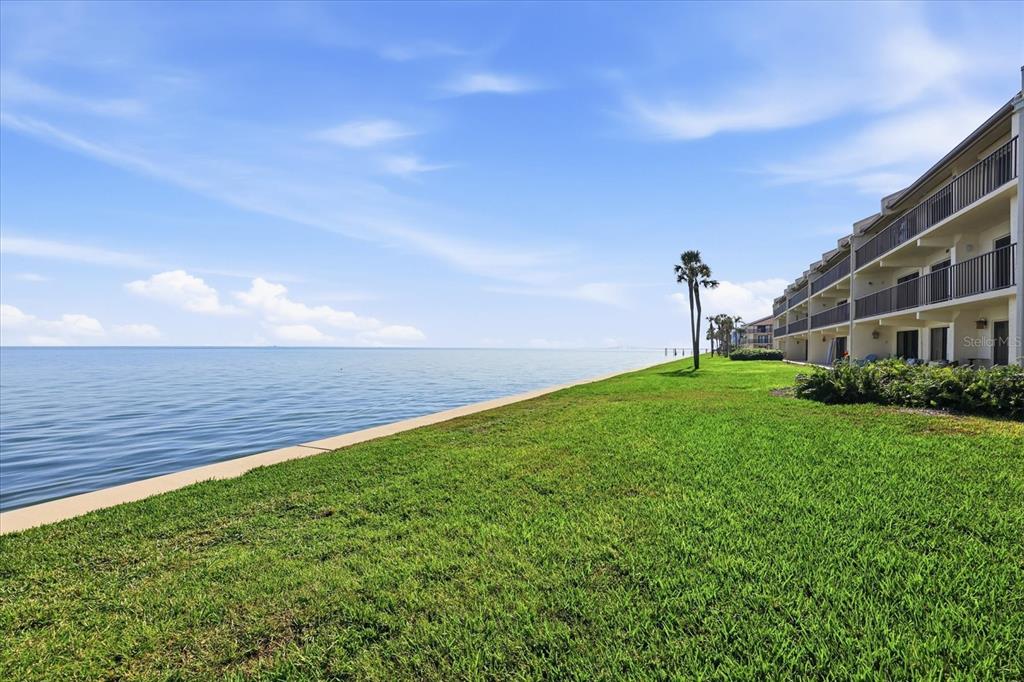 A multi-story apartment building sits beside a large body of water and a grassy lawn — 7520 SUNSHINE SKYWAY LANE S UNIT T19, ST PETERSBURG, FL