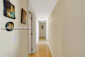 A hallway with light-colored walls, tile flooring, and several framed pictures hanging on the wall — 9125 SW 77th Ave # 802, Miami FL 33156, MIAMI, FL