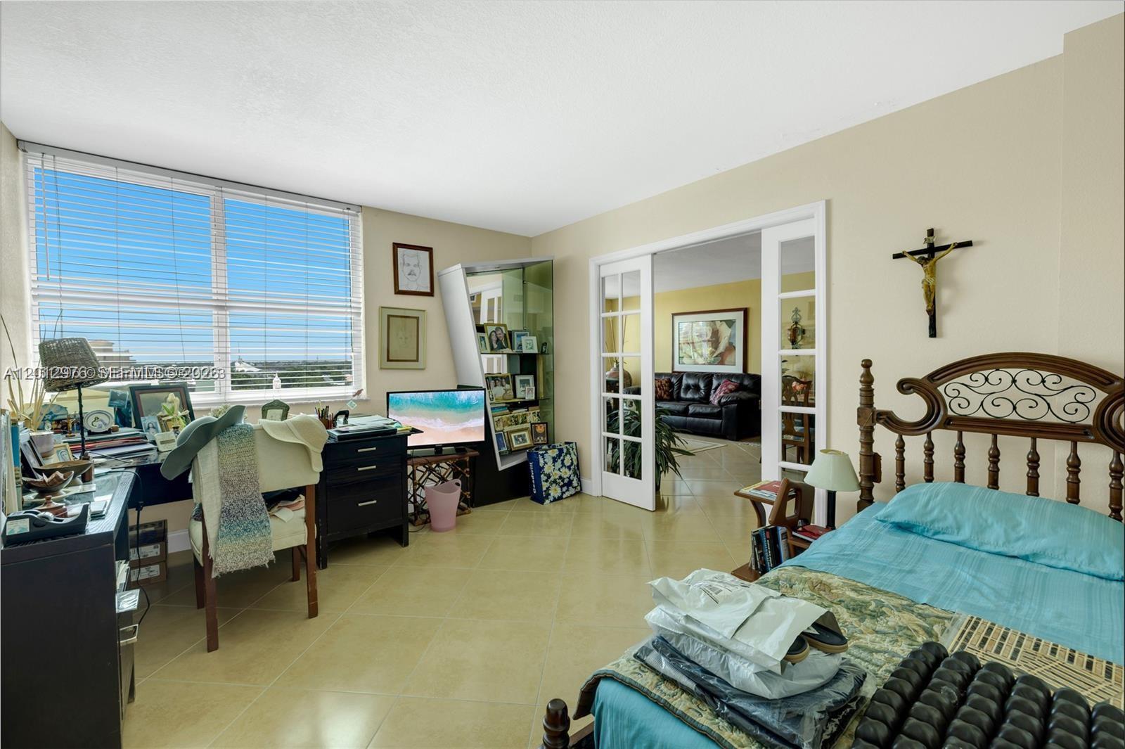 A bedroom with tile floors, a bed, a desk, and French doors leading to another room — 9125 SW 77th Ave # 802, Miami FL 33156, MIAMI, FL
