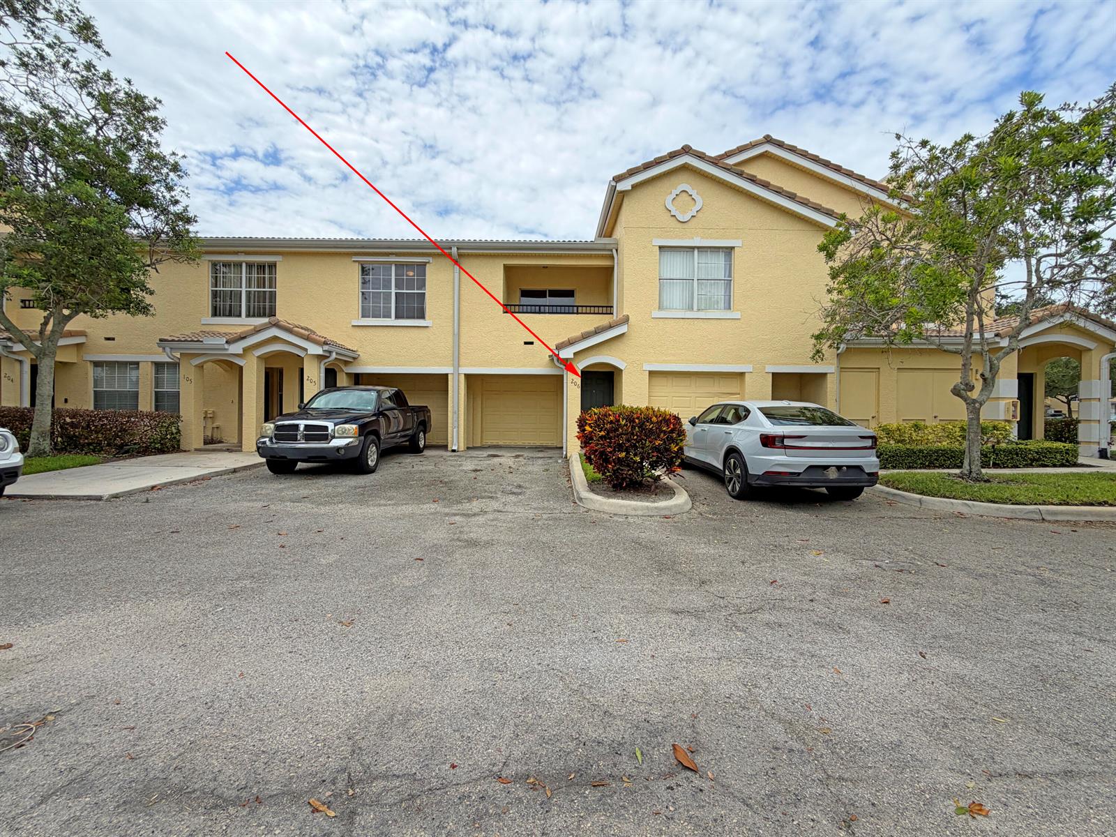 A two-story yellow townhouse with a garage and a red arrow pointing to the entrance — 124 SW Peacock Boulevard # 206, FL 34986, FL