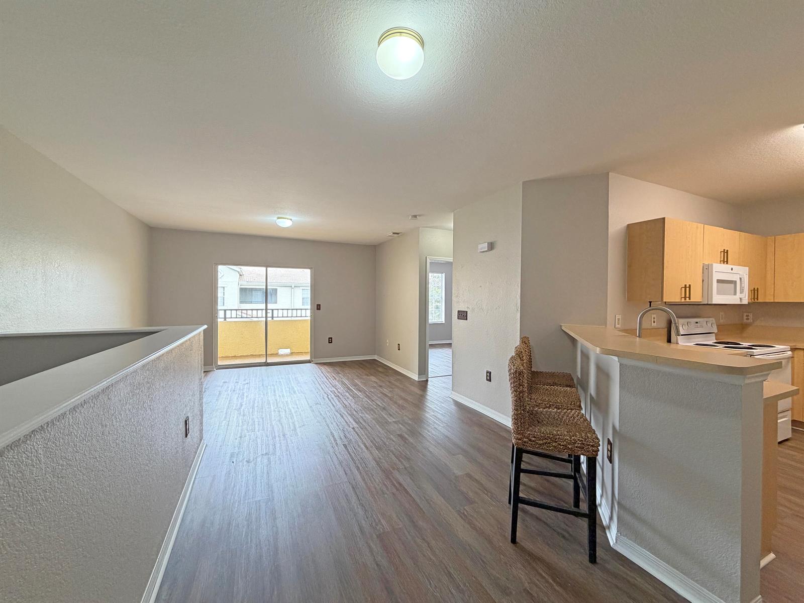 An open-concept living area features wood-look flooring, a kitchen breakfast bar, and a sliding door — 124 SW Peacock Boulevard # 206, FL 34986, FL