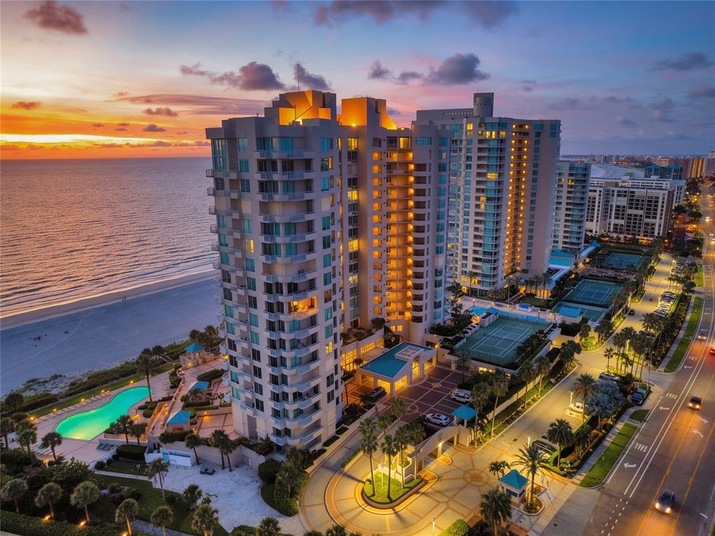 An aerial view of a high-rise beachfront condominium complex at sunset with a swimming pool — 1560 GULF BOULEVARD UNIT 0000, CLEARWATER BEACH, FL