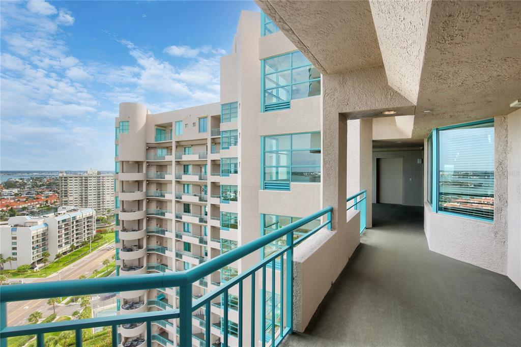 A high-rise balcony with teal railings overlooks a coastal city and neighboring apartment buildings — 1560 GULF BOULEVARD UNIT 0000, CLEARWATER BEACH, FL