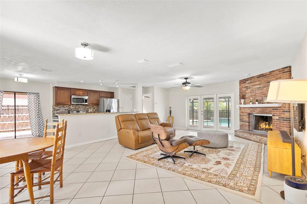 An open-concept living and dining area features tile floors, a brick fireplace, and kitchen cabinetry — 15701 COUNTRY LAKE DRIVE, TAMPA, FL