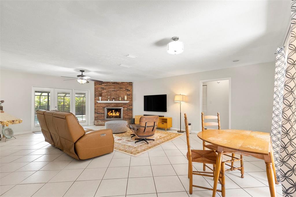 A living room with tile floors, a brick fireplace, and a dining area — 15701 COUNTRY LAKE DRIVE, TAMPA, FL