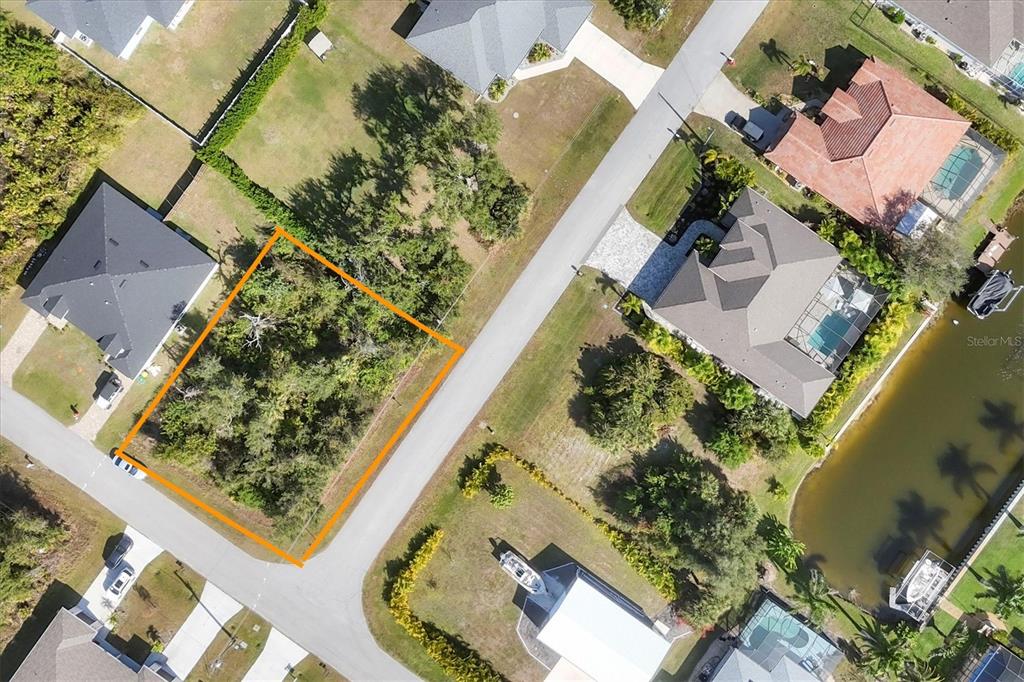 This aerial view shows a vacant, wooded residential lot outlined in orange along a street — 13445 AMARYLLIS CIRCLE, PORT CHARLOTTE, FL
