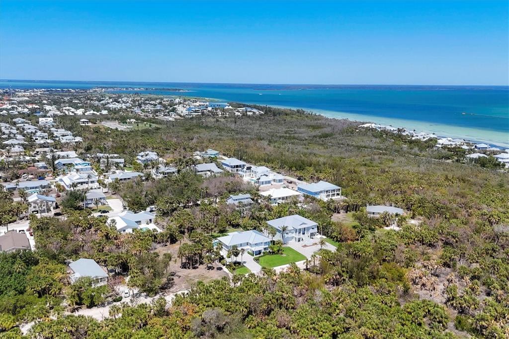 An aerial view shows houses nestled among trees near a coastline with blue water — 355 BARBAROSA STREET, BOCA GRANDE, FL