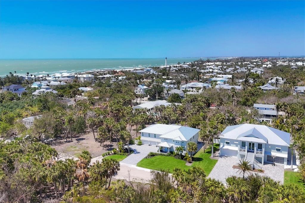 An aerial view shows two white houses with metal roofs surrounded by lush tropical vegetation — 355 BARBAROSA STREET, BOCA GRANDE, FL
