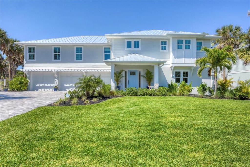 A two-story light blue house with a metal roof, white trim, and a paved driveway — 355 BARBAROSA STREET, BOCA GRANDE, FL