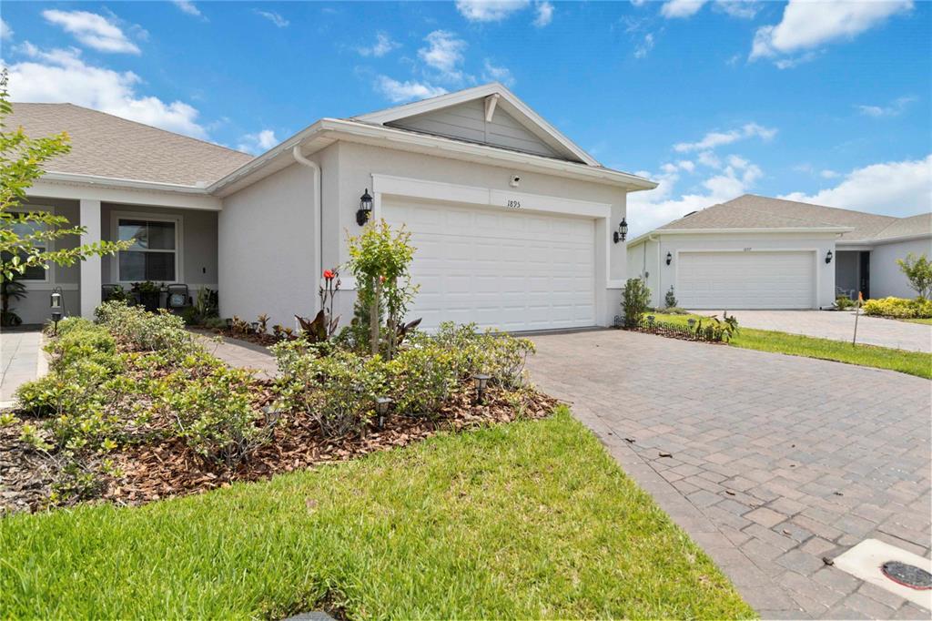 A single-story house with a white garage, gray siding, and a paved driveway — 1895 SPRING SHOWER CIRCLE, KISSIMMEE, FL