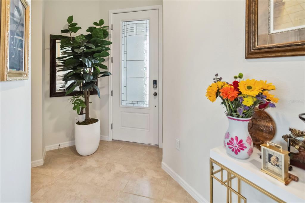 An entryway features a white front door, a potted plant, and a floral vase — 1895 SPRING SHOWER CIRCLE, KISSIMMEE, FL