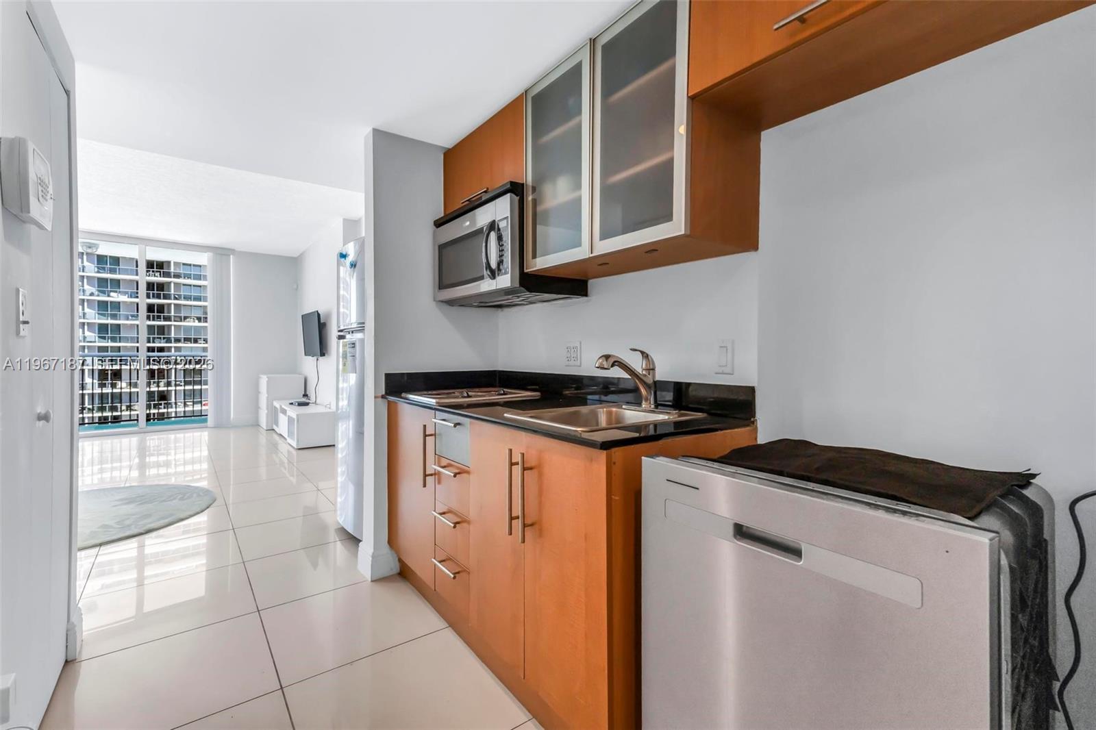 A small kitchen features wood cabinets, black countertops, and a stainless steel dishwasher — 1750 N Bayshore Dr # 4507, Miami FL 33132, MIAMI, FL