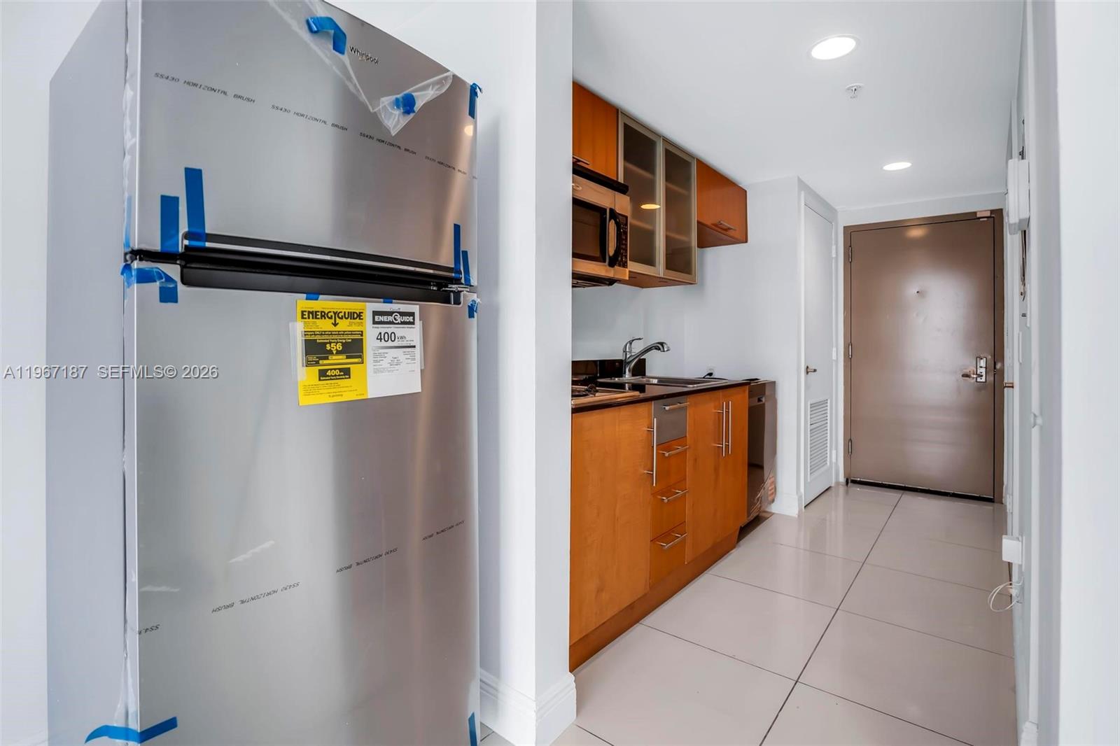 A kitchen features stainless steel appliances, wood cabinets, and light tile flooring — 1750 N Bayshore Dr # 4507, Miami FL 33132, MIAMI, FL
