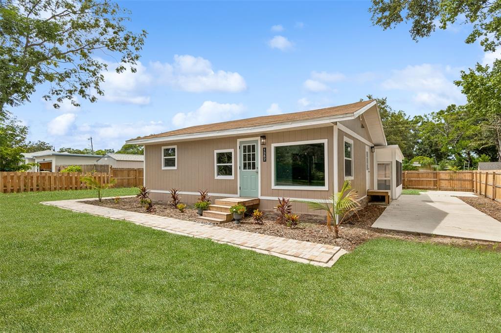 A tan, single-story house with a light blue front door and a brick walkway — 1362 MILTON STREET, CLEARWATER, FL