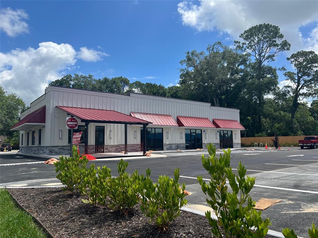 A newly constructed commercial building with a white metal facade and red awnings — 24974 SW 4 AVENUE, NEWBERRY, FL