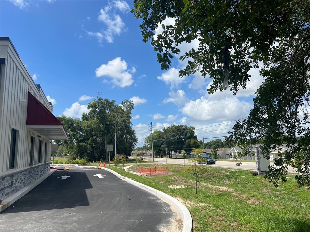 A paved drive-thru lane runs alongside a modern building with a red awning — 24974 SW 4 AVENUE, NEWBERRY, FL
