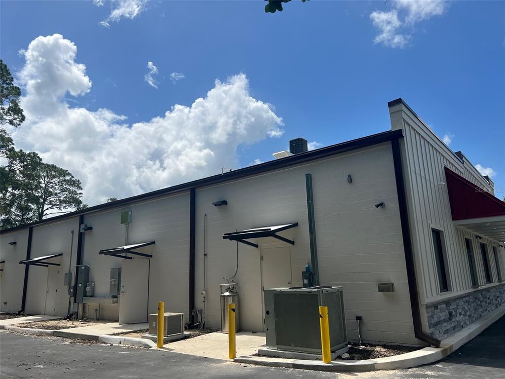 The exterior of a commercial building features concrete block walls, metal awnings, and utility equipment — 24974 SW 4 AVENUE, NEWBERRY, FL