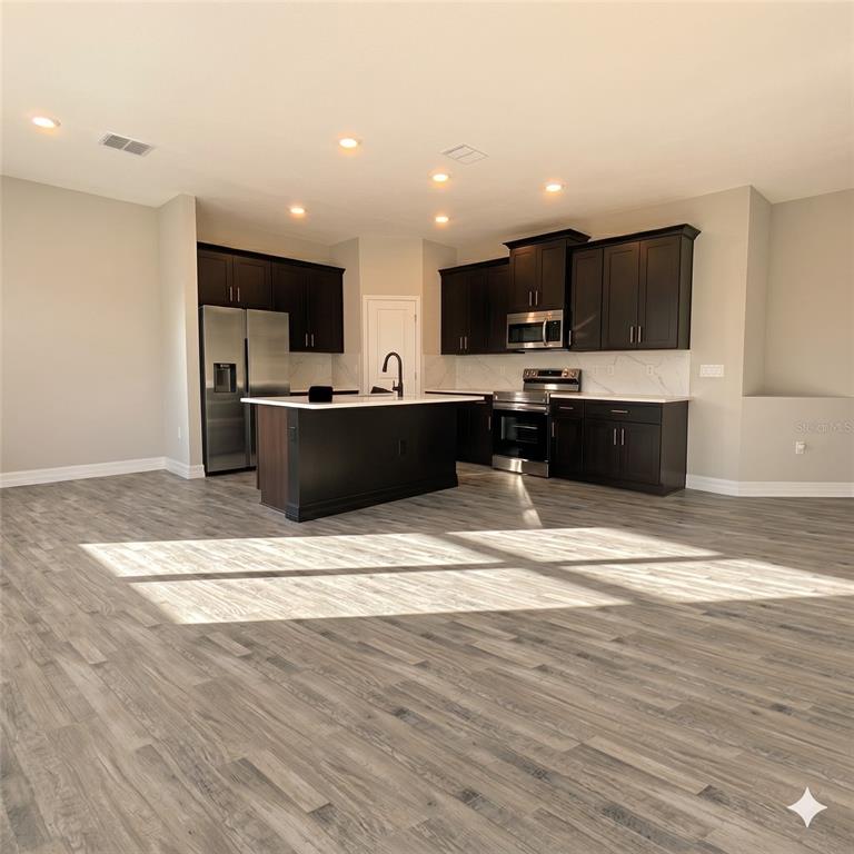 A modern kitchen features dark wood cabinets, stainless steel appliances, and a central island — 2039 E NEWHAVEN STREET, INVERNESS, FL