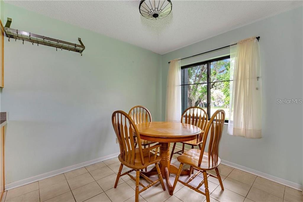 A dining area features a round wooden table, four chairs, tile flooring, and a window — 7 BUCK CIRCLE UNIT 7, HAINES CITY, FL