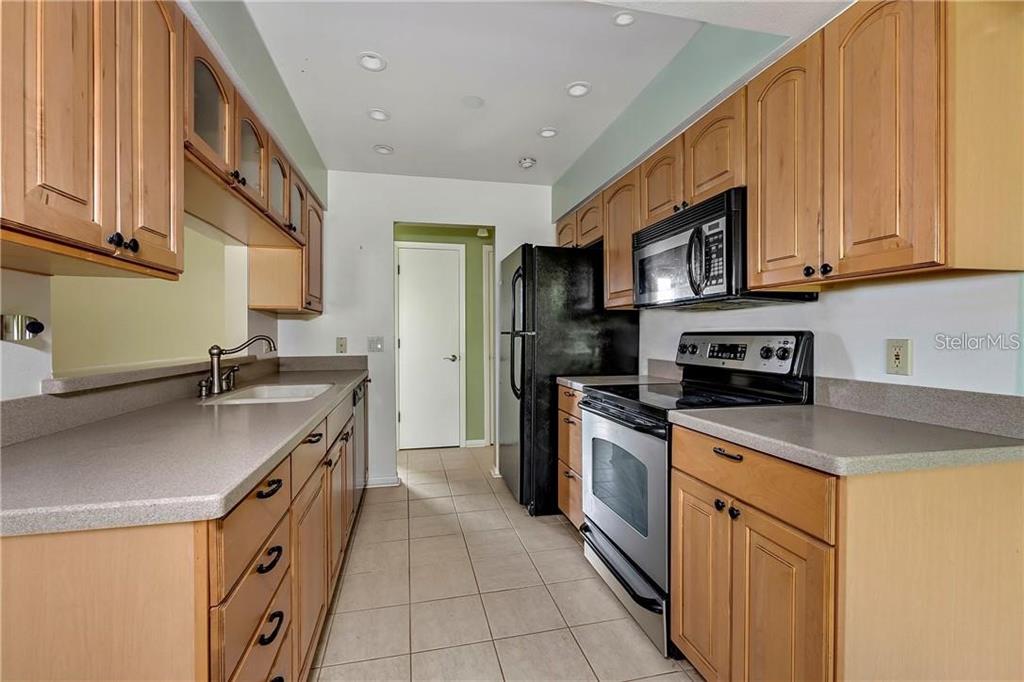 A kitchen with light wood cabinets, gray countertops, and black appliances on a tiled floor — 7 BUCK CIRCLE UNIT 7, HAINES CITY, FL