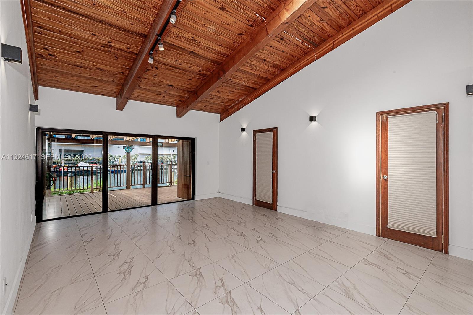 A room with a wood-beamed ceiling, tile flooring, and sliding glass doors opening to a deck — 2621 S Parkview Dr, Hallandale Beach FL 33009, HALLANDALE BEACH, FL