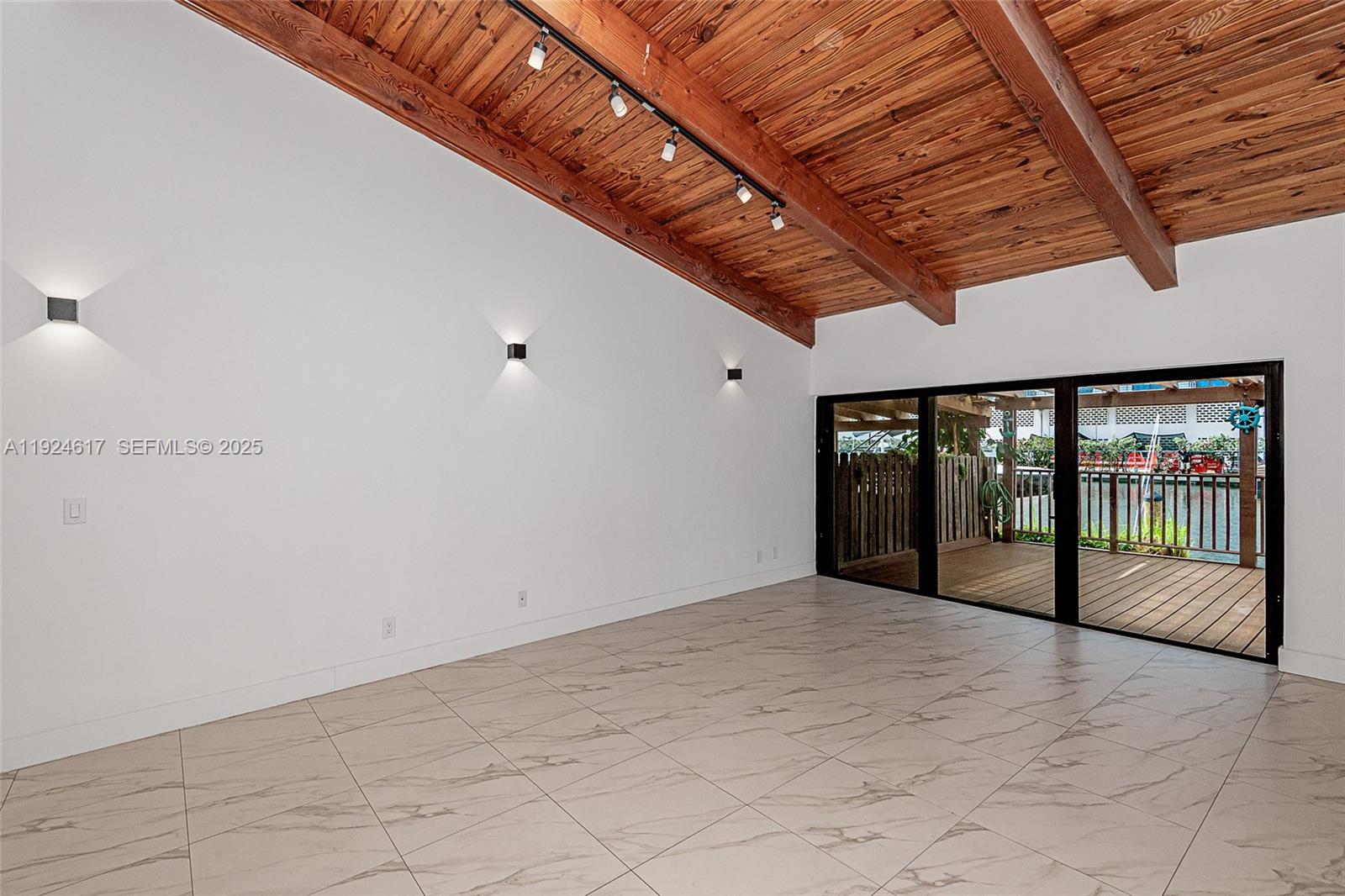 An empty room features a vaulted wood-paneled ceiling, white walls, tile flooring, and sliding glass doors — 2621 S Parkview Dr, Hallandale Beach FL 33009, HALLANDALE BEACH, FL