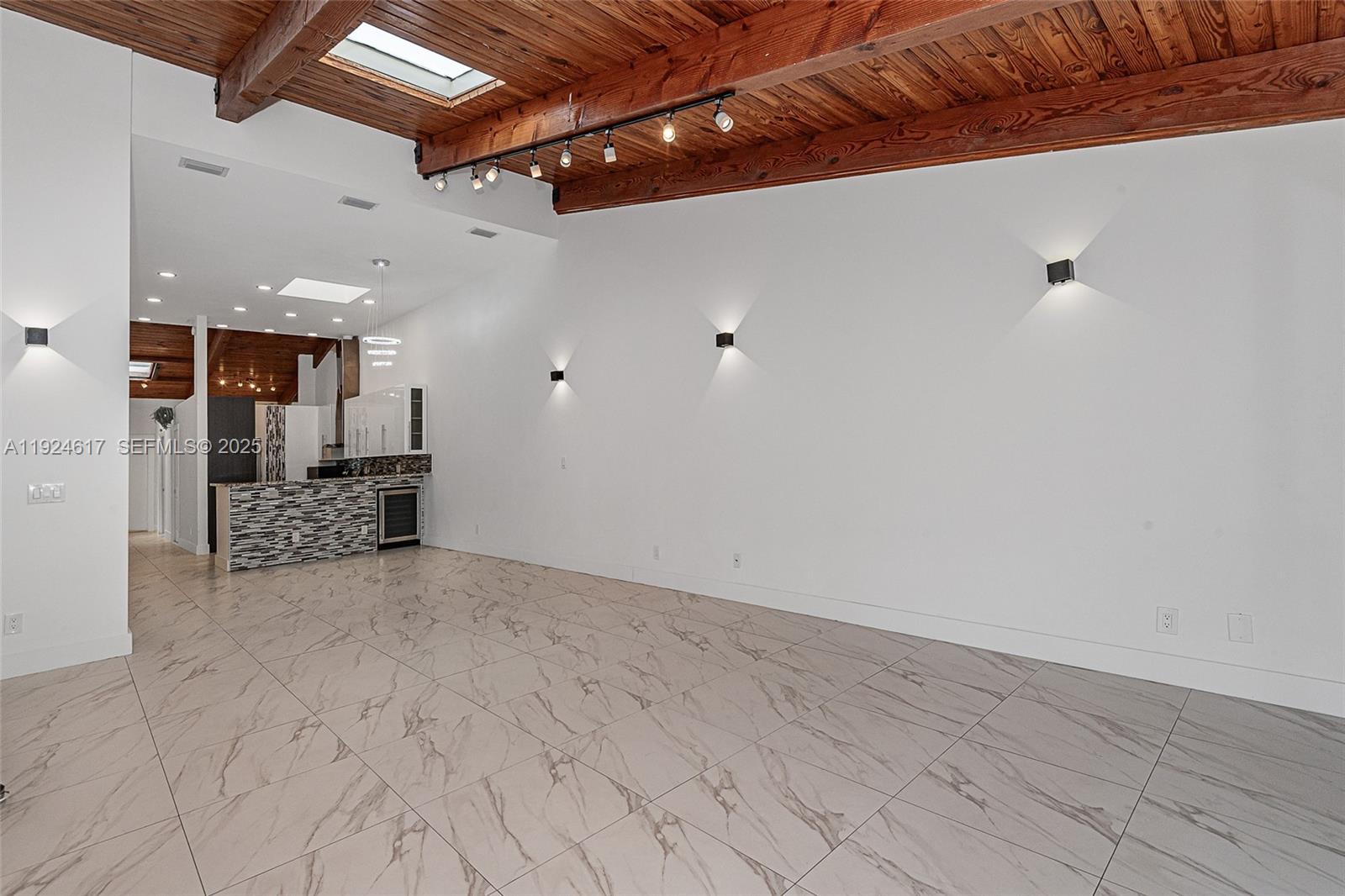 An open living area features a wood-beamed ceiling, skylights, marble-look tile floors, and wall sconces — 2621 S Parkview Dr, Hallandale Beach FL 33009, HALLANDALE BEACH, FL
