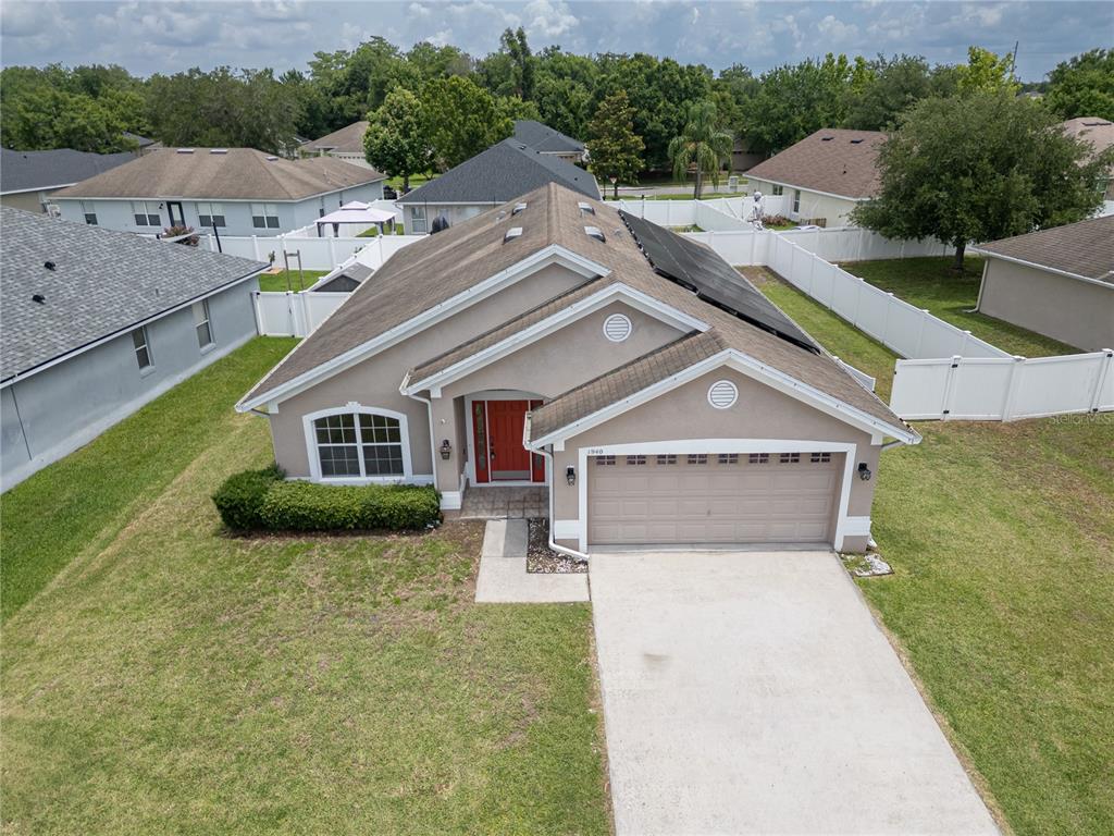 An aerial view of a single-story suburban house with a tan exterior and red door — 1940 FAWN MEADOW CIRCLE, ST CLOUD, FL