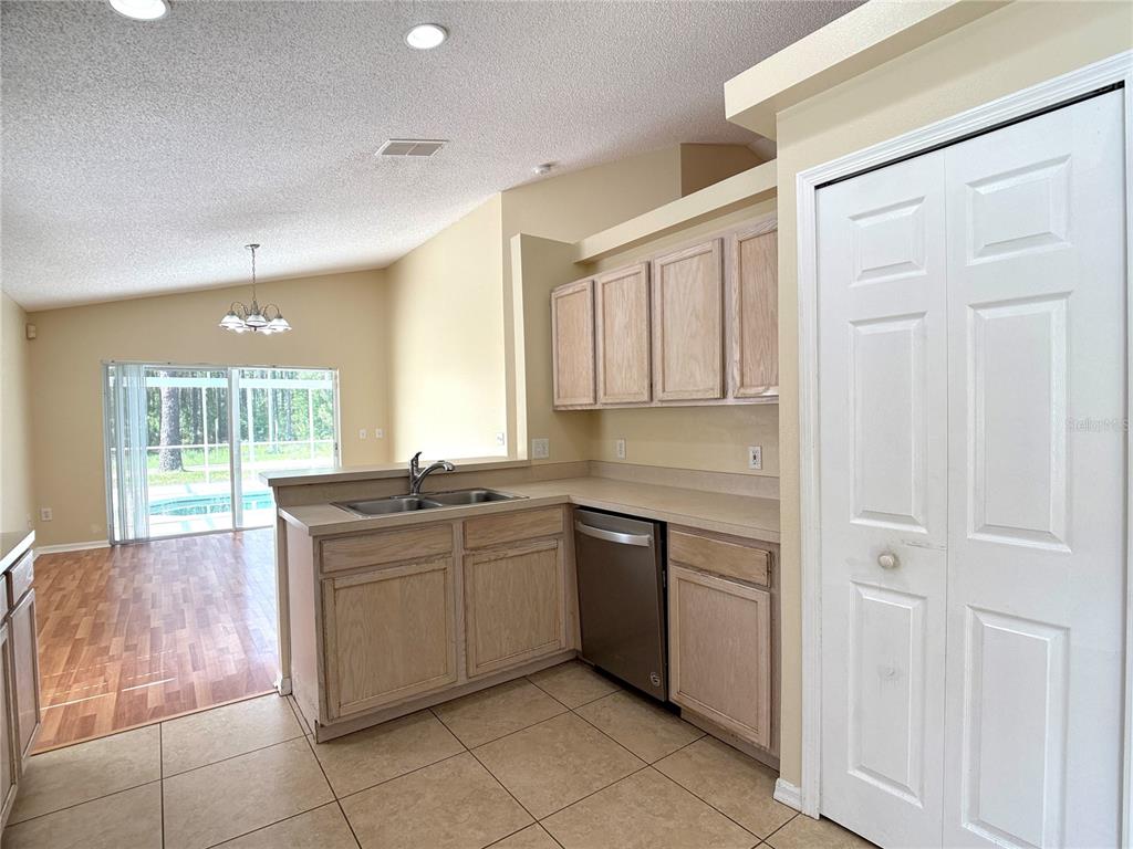 A kitchen with light wood cabinets, tile flooring, and a view of a backyard pool — 526 PINE CONE DRIVE, DAVENPORT, FL