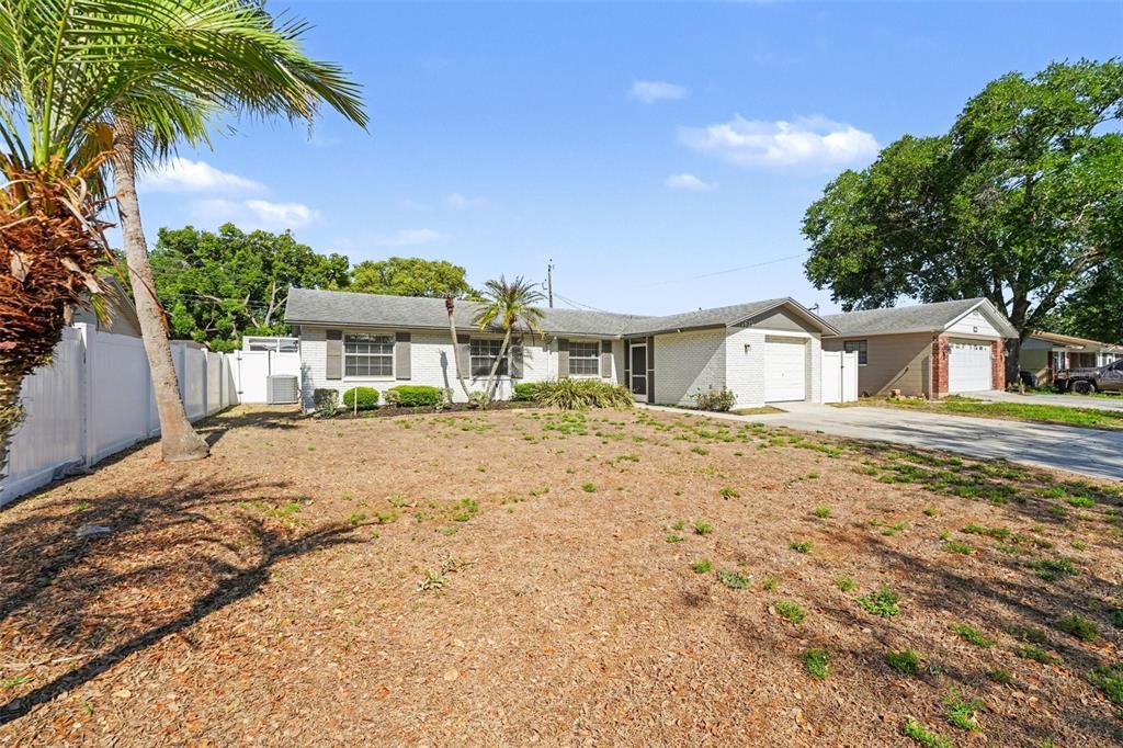 A single-story white brick house with a front-facing garage and a dry, patchy lawn — 1615 SENECA AVENUE, LAKELAND, FL