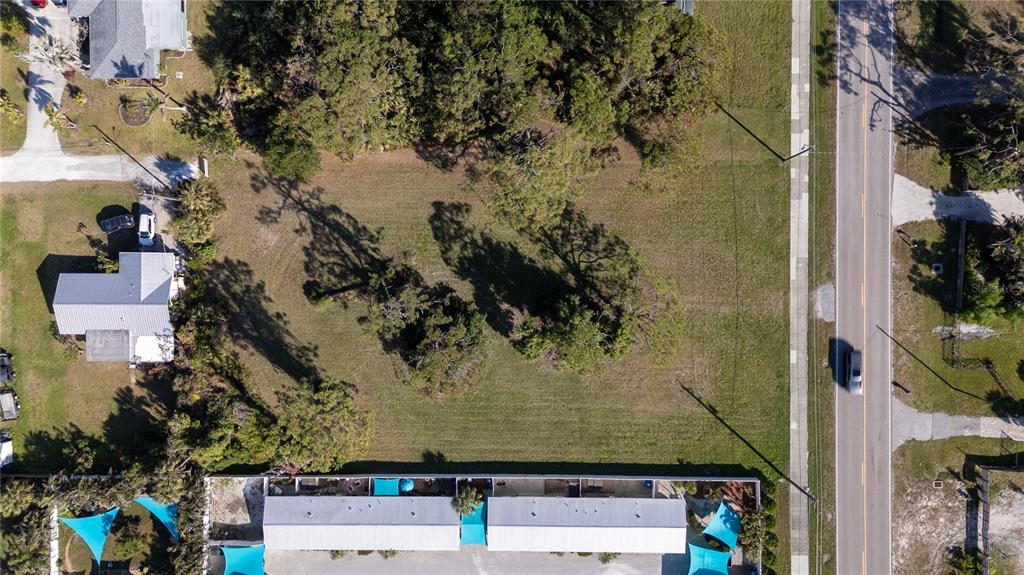An aerial view shows a vacant, grassy rectangular lot bordered by a road and buildings — OLD ENGLEWOOD ROAD, ENGLEWOOD, FL