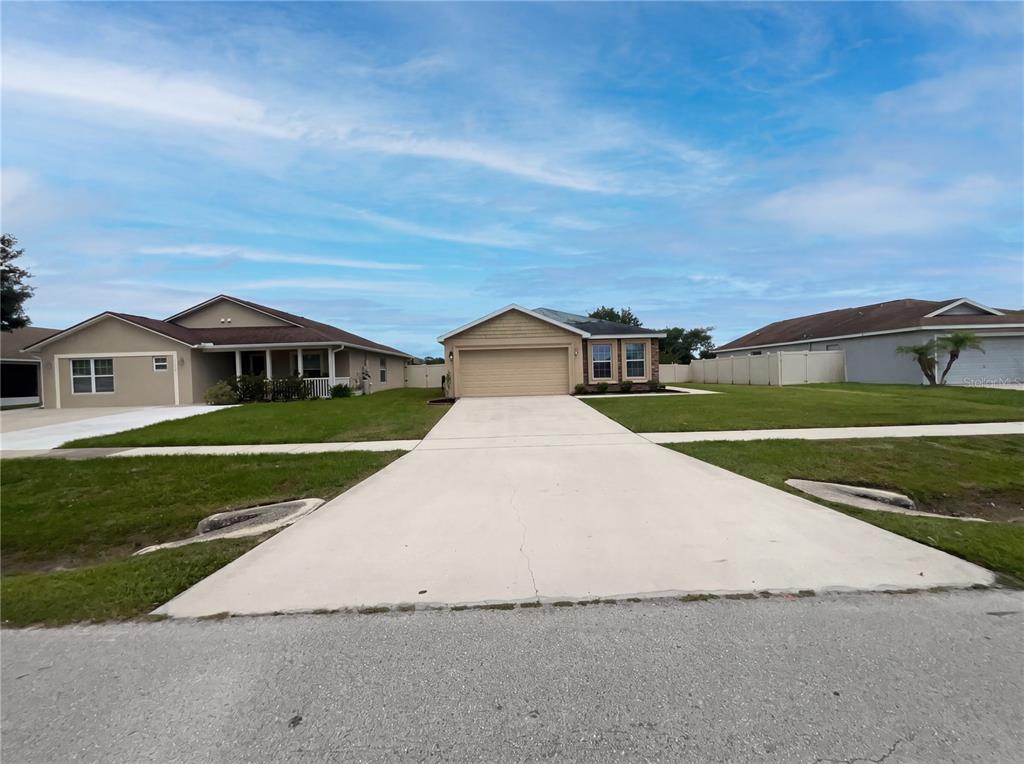 A single-story house with a beige exterior, a two-car garage, and a concrete driveway — 2005 ORANGE AVENUE, ST CLOUD, FL