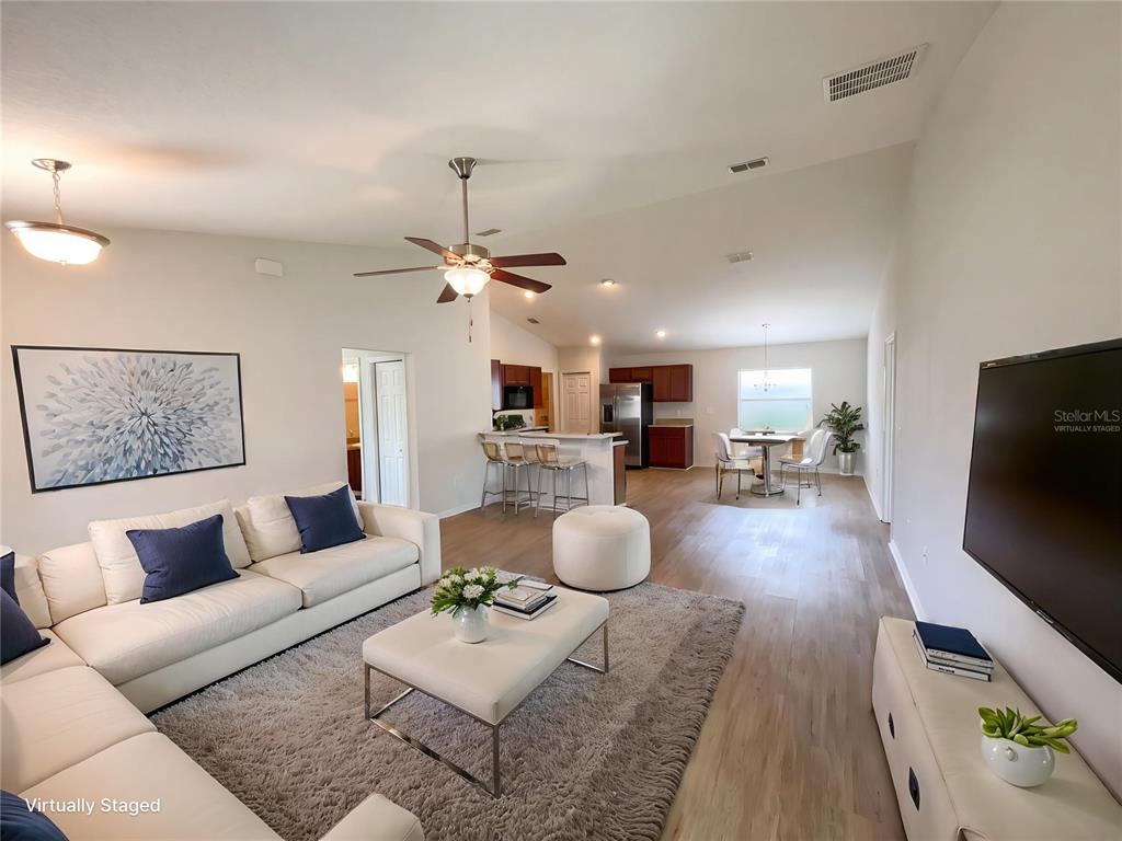 A living room with a white sofa and coffee table opens into a kitchen area — 2005 ORANGE AVENUE, ST CLOUD, FL