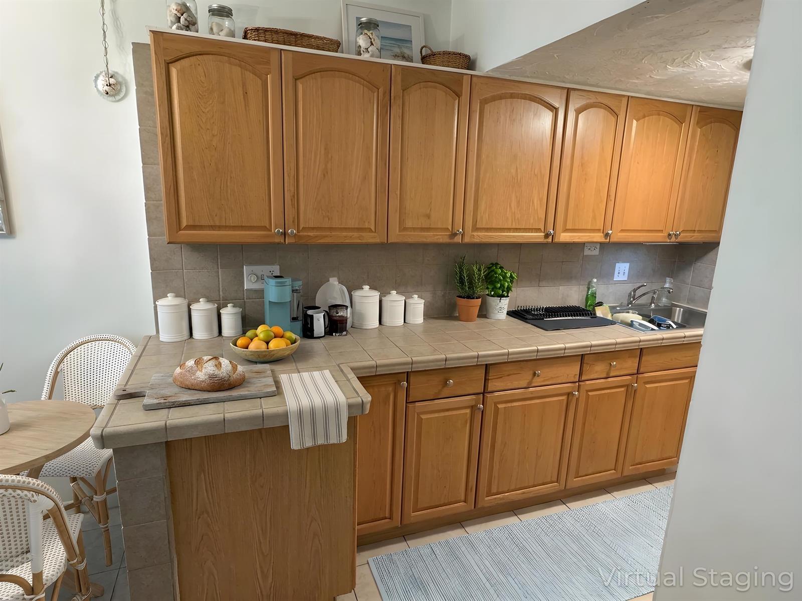 A kitchen with wood cabinets, tiled countertops, and a small dining area — 702 N Federal Highway # A8, FL 33460, FL