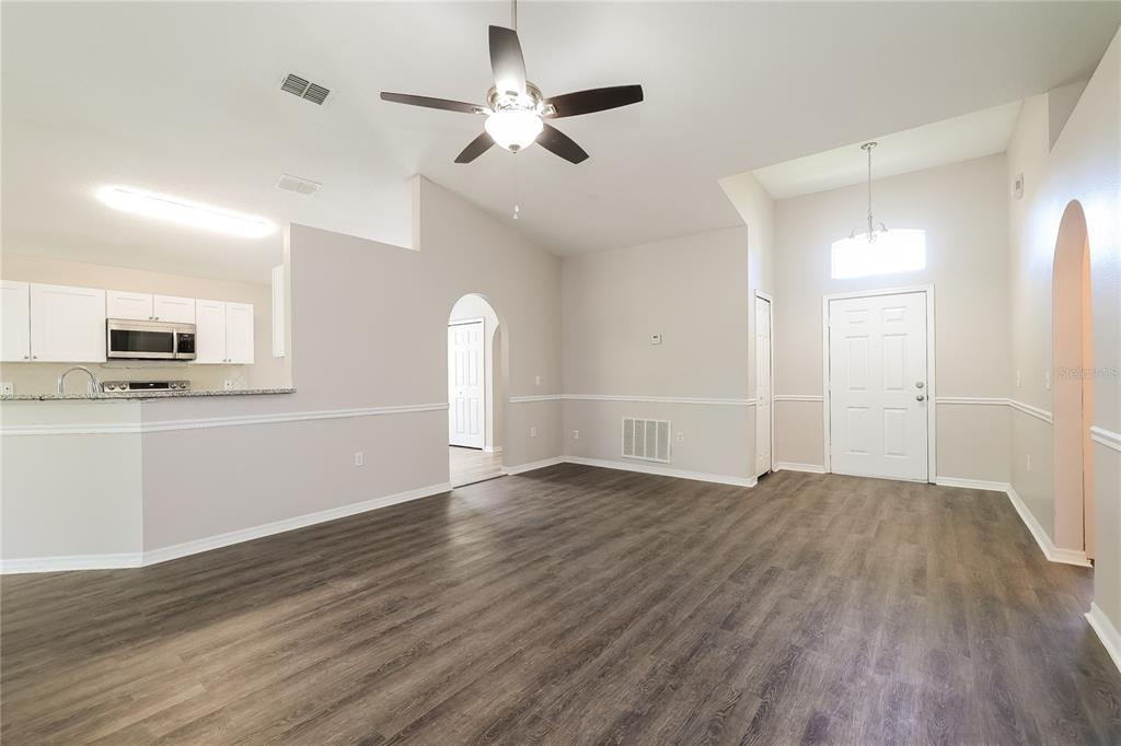 An open-concept living area features wood-look flooring, a ceiling fan, and an adjacent kitchen — 416 ELGIN BOULEVARD, DAVENPORT, FL
