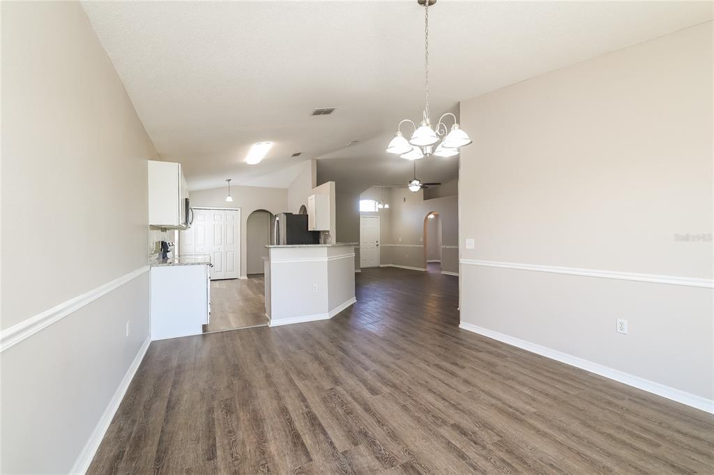 An open-concept dining area features wood-look flooring, beige walls with chair rail molding, and a chandelier — 416 ELGIN BOULEVARD, DAVENPORT, FL